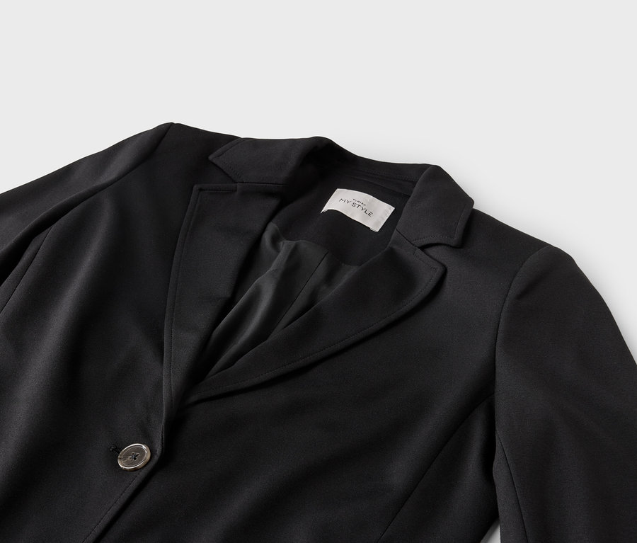 Gros plan sur un blazer noir avec un col à revers et un bouton.