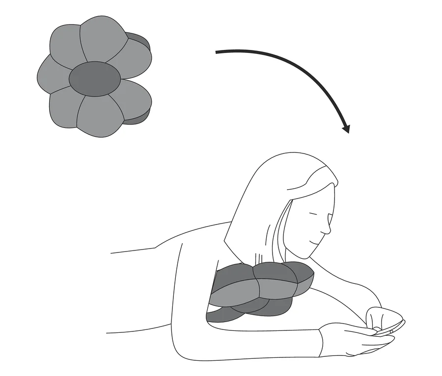 Une femme est allongée avec un coussin de relaxation multifonction sous la tête et regarde son téléphone.
