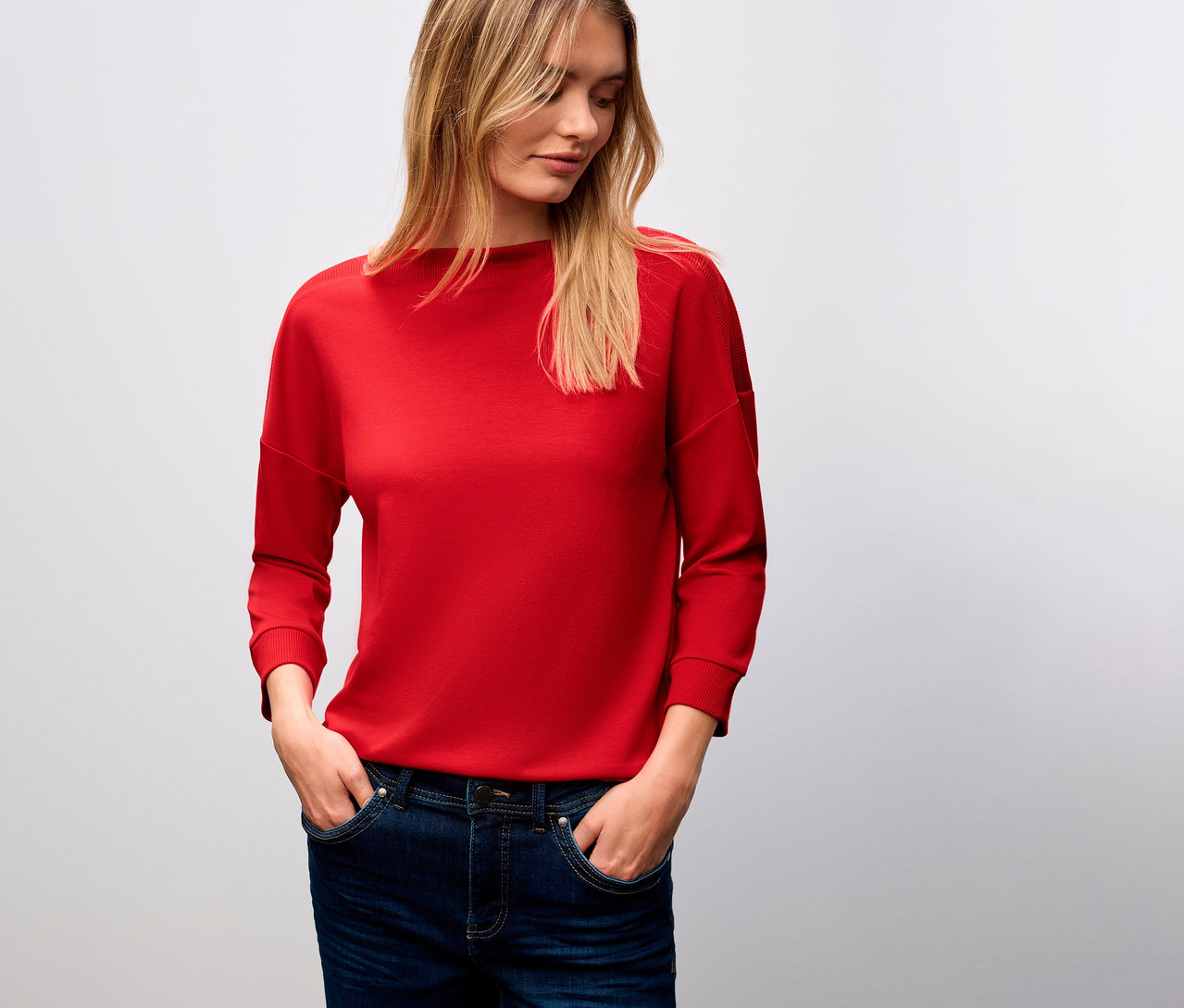 Femme blonde portant un t-shirt avec détails côtelés Street One rouge et un jean.
