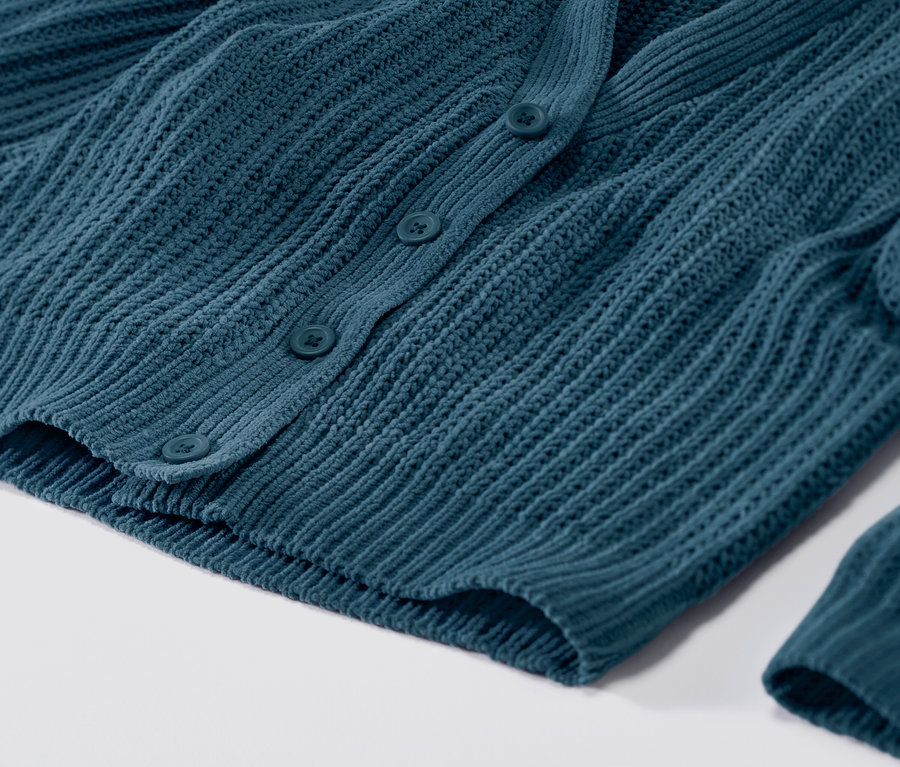 Gros plan sur un cardigan en maille pétrole avec des boutons.