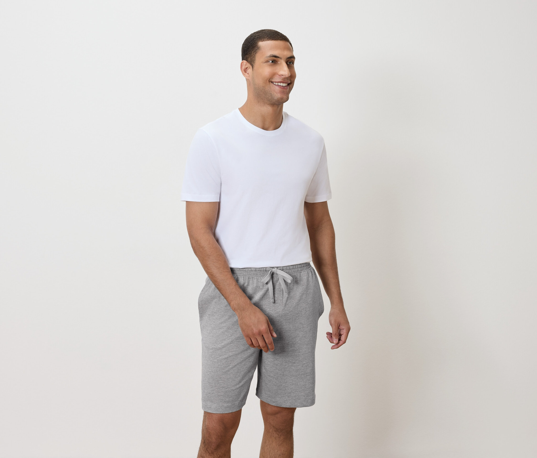 Un homme porte un t-shirt blanc et un short gris.