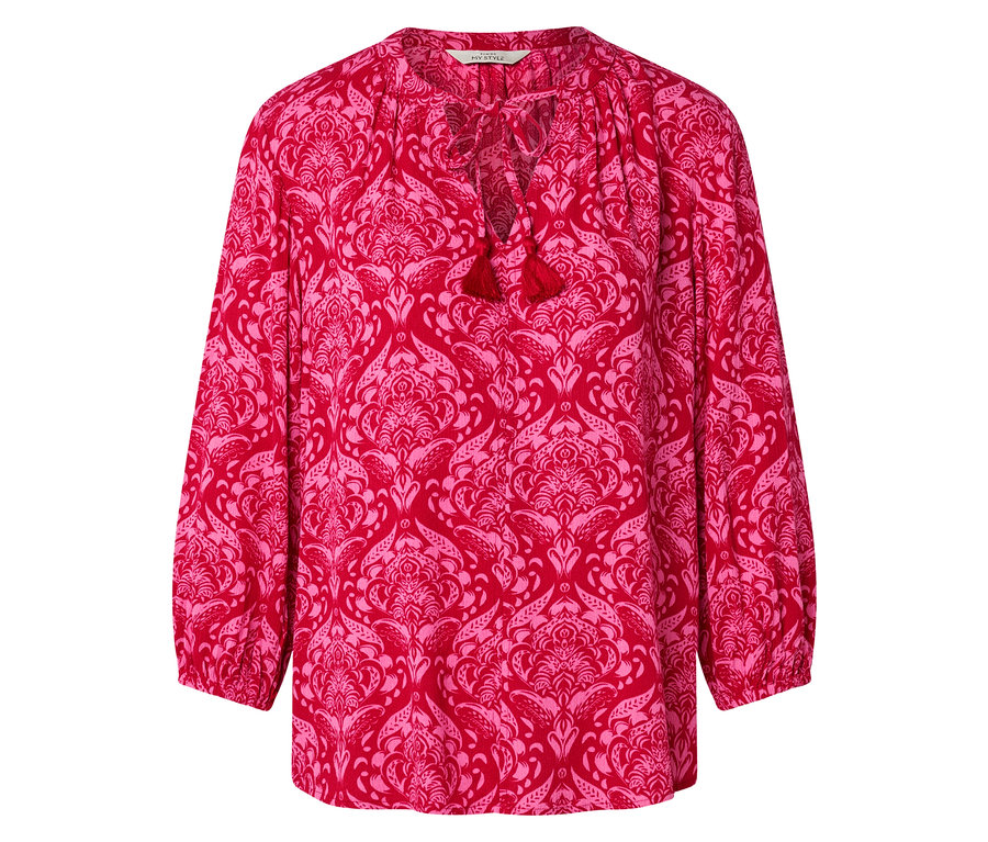 Chemisier rouge à motif floral rose avec des pompons à l'encolure.