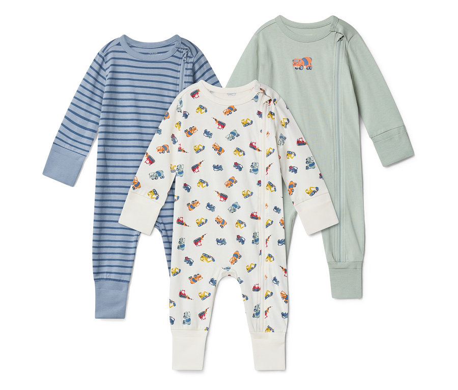 Trois pyjamas pour bébés sont posés sur un fond blanc. Celui de gauche est rayé bleu, celui du milieu est blanc avec des camions de chantier colorés et celui de droite est vert clair avec un éléphant.