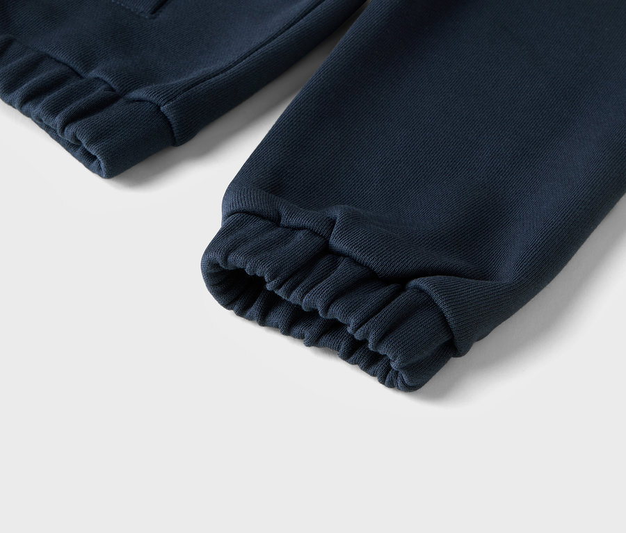 Gros plan d'un pantalon de survêtement bleu marine avec des poignets côtelés.
