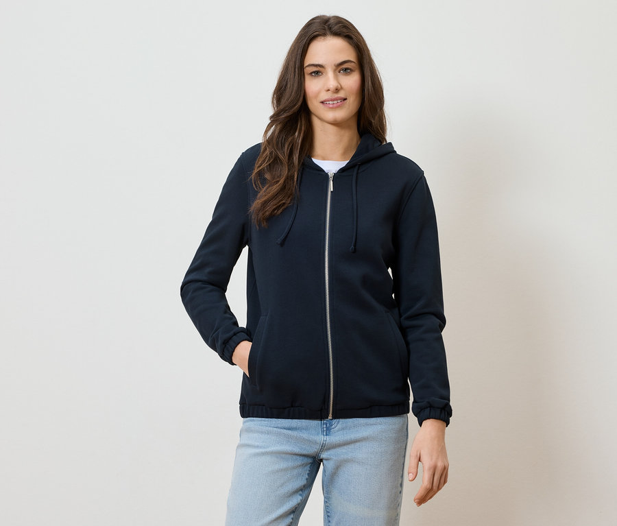 Femme portant un sweat à capuche bleu marine zippé et un jean.