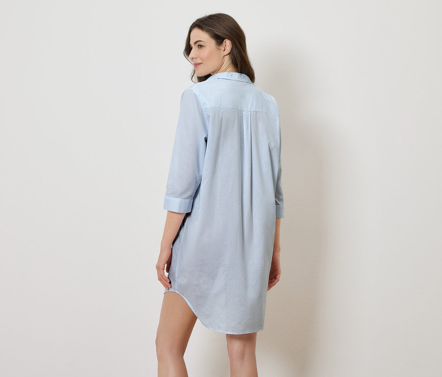 Femme vue de dos portant une robe chemise bleu clair à rayures.