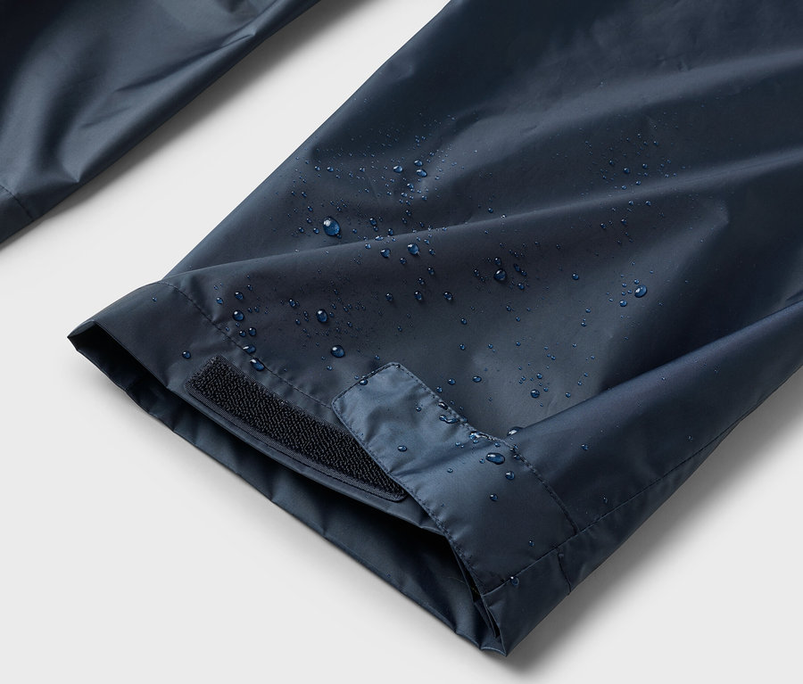 Gros plan sur des manches bleu marine hydrofuges avec fermeture Velcro et gouttes d'eau.