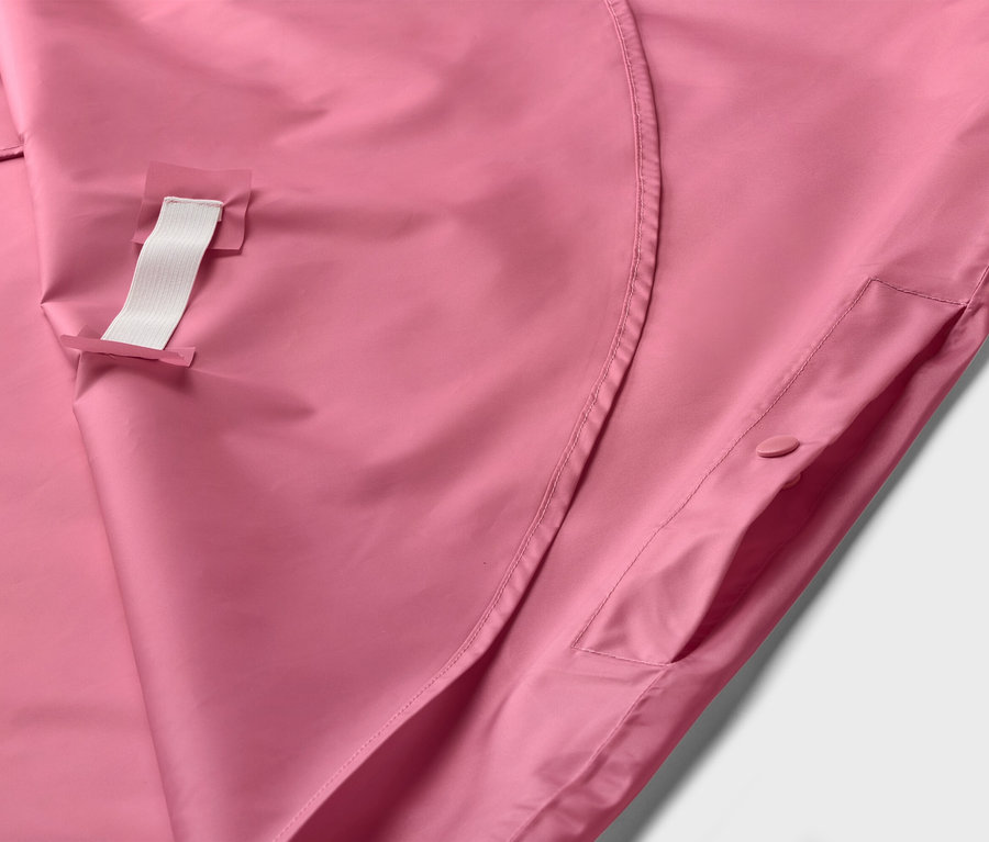 Gros plan sur une veste rose avec une boucle blanche et une poche boutonnée.