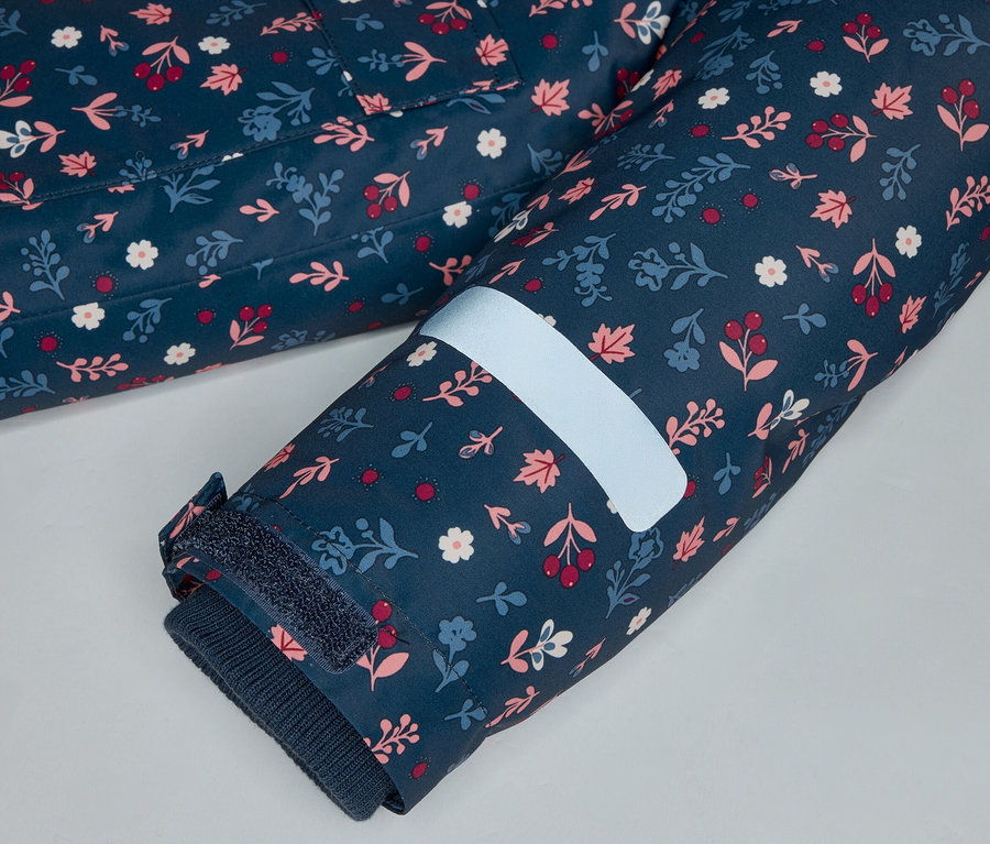 Gros plan sur une manche bleu marine à motif floral avec une bande réfléchissante et une fermeture velcro.