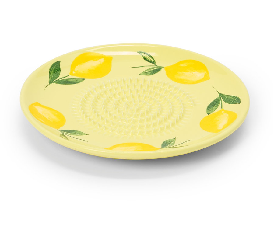 Une râpe en céramique jaune avec un motif de citron repose sur un fond blanc.
