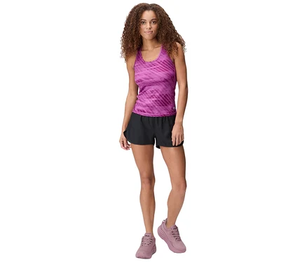 Femme debout portant un débardeur rose à motifs, un short technique pour femme FILA noir et des baskets roses.