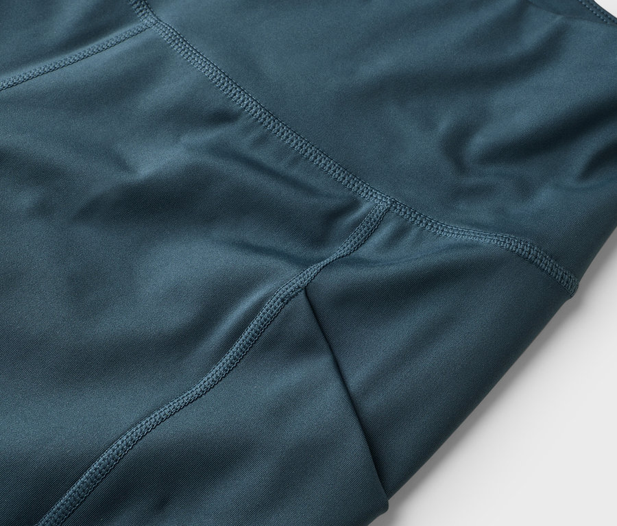 Gros plan sur un legging bleu avec des coutures apparentes.