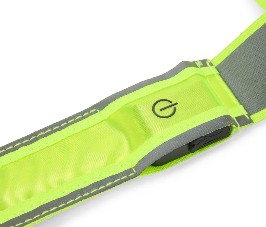 Gros plan d'une sangle réfléchissante jaune fluo avec des bandes réfléchissantes grises, un symbole d'alimentation et une unité de commande sombre.