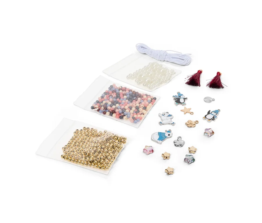 Kit de loisirs créatifs avec trois sachets de perles (dorées, multicolores, blanches), une cordelette blanche, deux pompons rouges et divers charms en forme de pingouins, ours polaires, étoiles et fleurs.