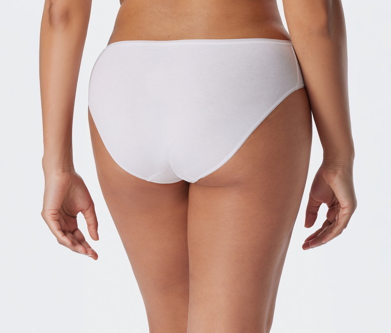 Vue de dos d'une personne portant une culotte blanche, les mains pendantes sur les côtés.