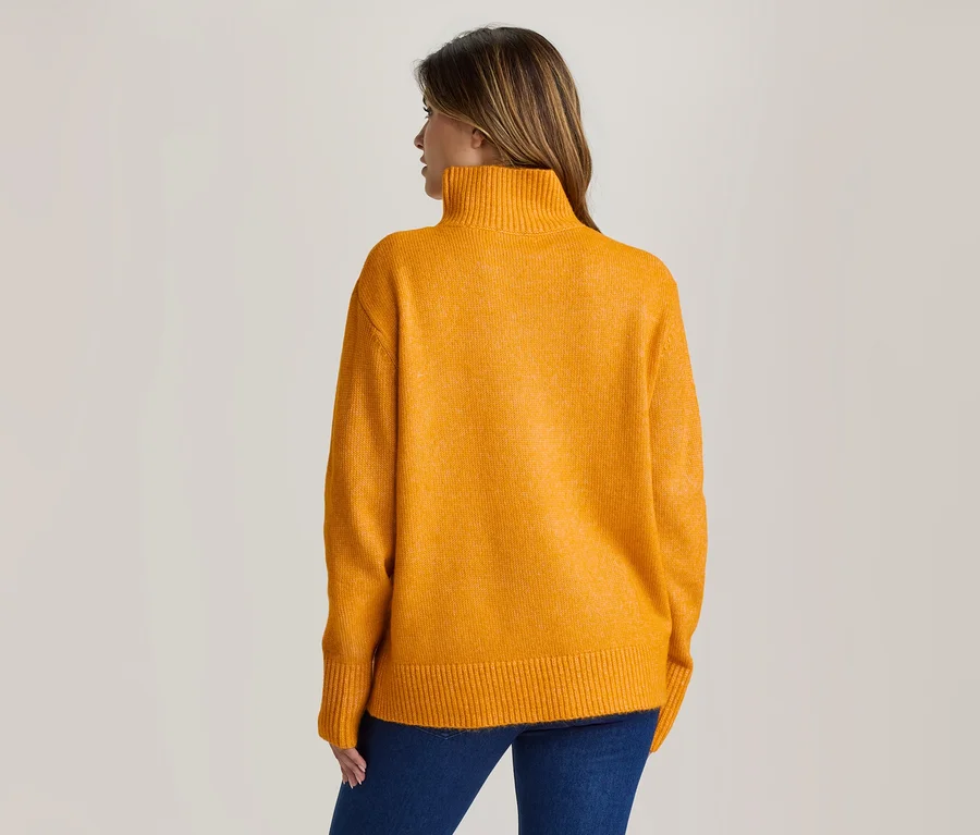 Femme de dos, portant un pull col roulé jaune et un jean bleu.