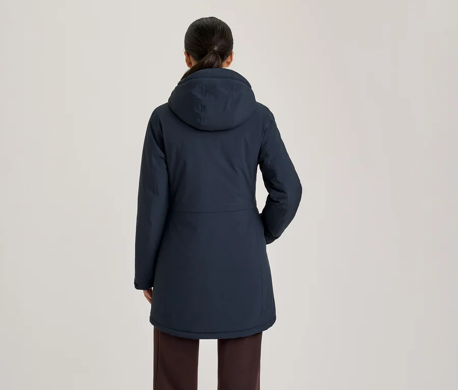 Femme vue de dos portant une veste à capuche bleu foncé et un pantalon foncé.