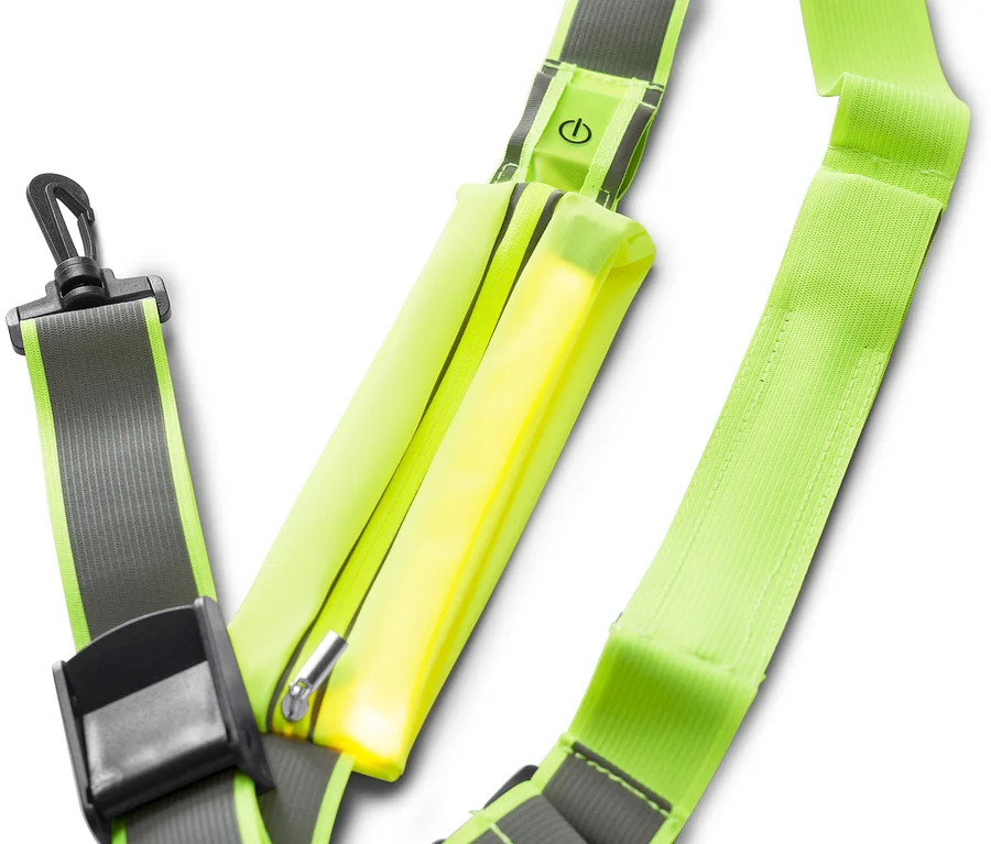 Harnais de sécurité vert néon avec une bande lumineuse jaune brillante, un bouton d'alimentation et des clips noirs, sur fond blanc.