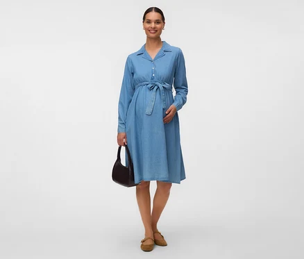 Femme enceinte portant une robe chemise en jean bleu avec une ceinture à nouer, un sac à main marron foncé et des chaussures plates marron clair.