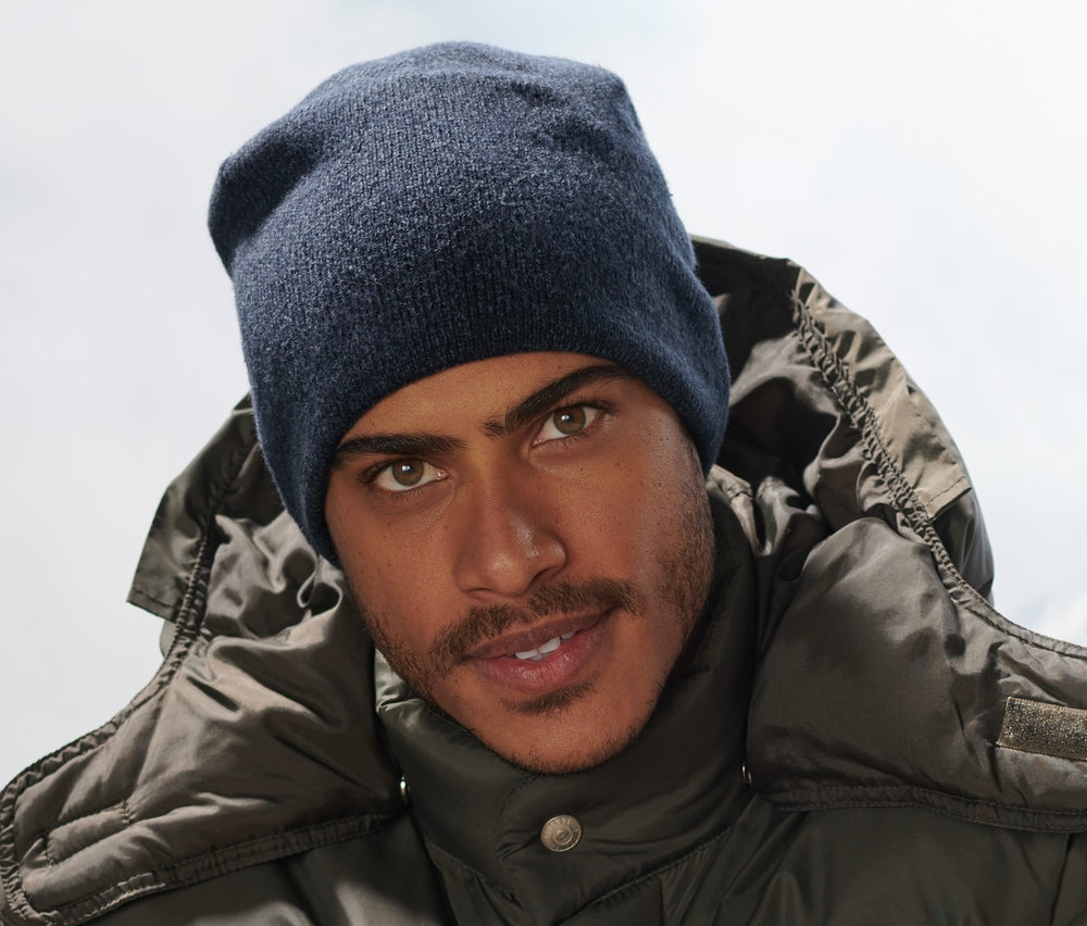 Un homme est assis sur un banc et porte un bonnet en maille bleu foncé.