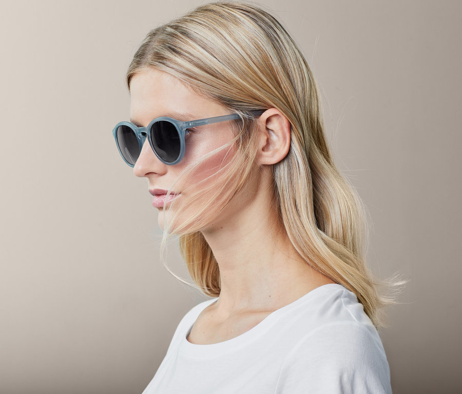 Profil d'une femme blonde portant des lunettes de soleil bleu clair.