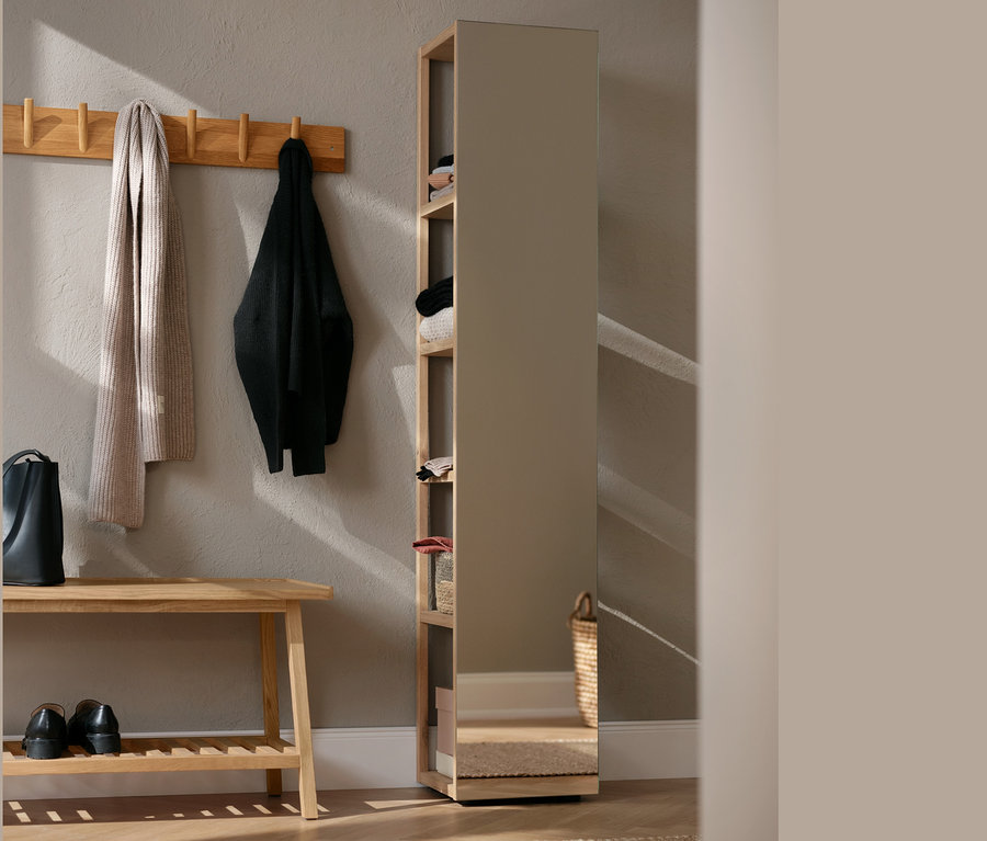 Dans le couloir, il y a une garde-robe murale en bois massif, des chaussures et un sac à main. Un porte-manteau avec une écharpe et une veste est accroché au mur.
