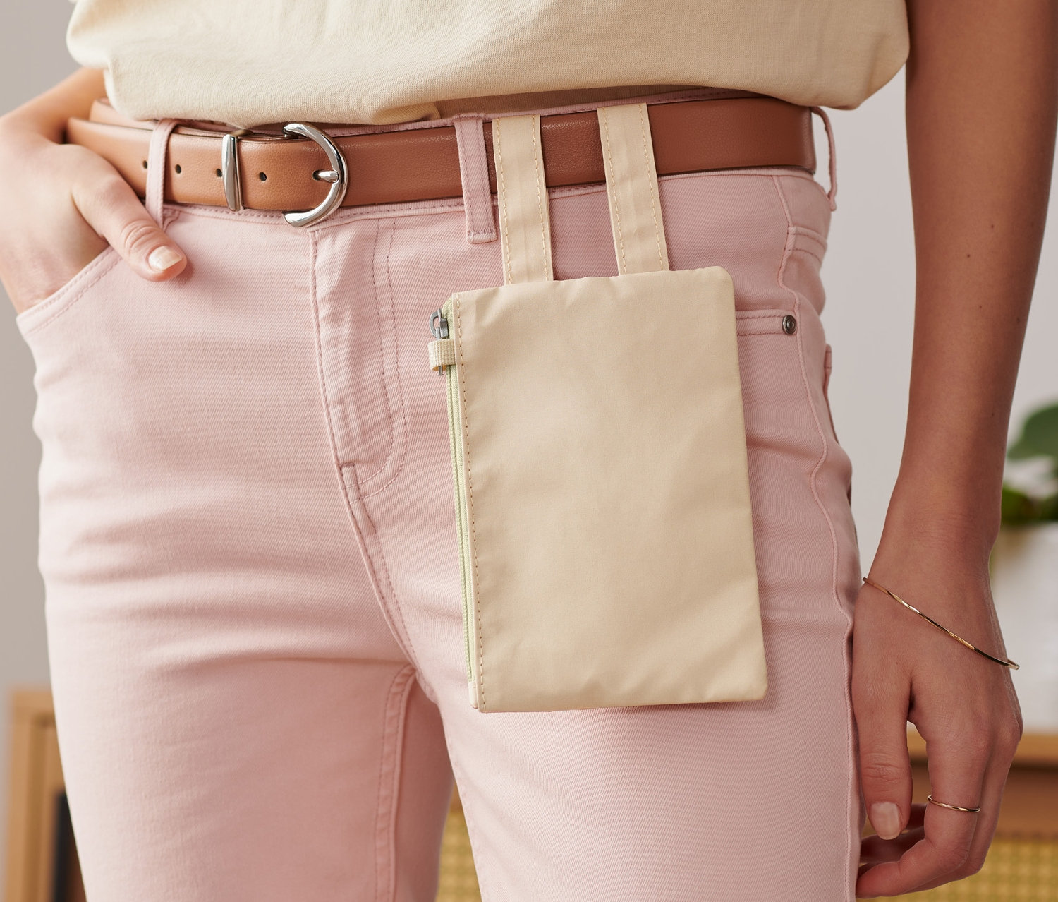 Une femme porte un jean rose et un sac banane.