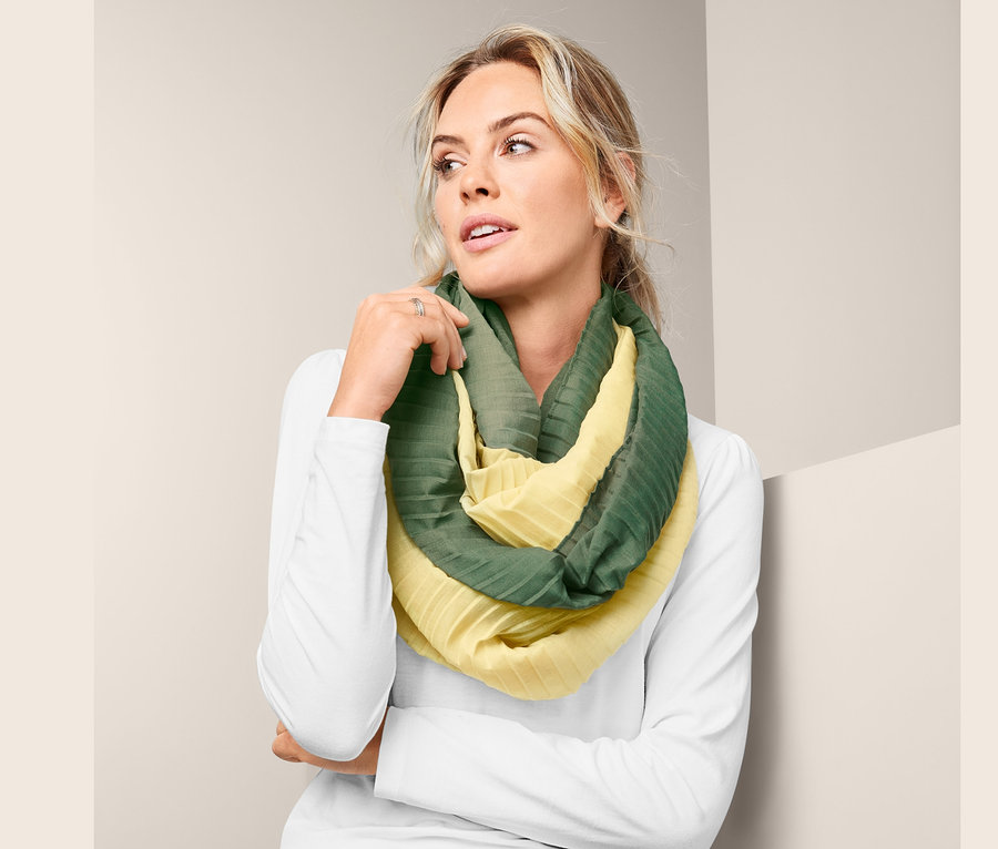 Une femme porte une écharpe tube plissée jaune et verte.