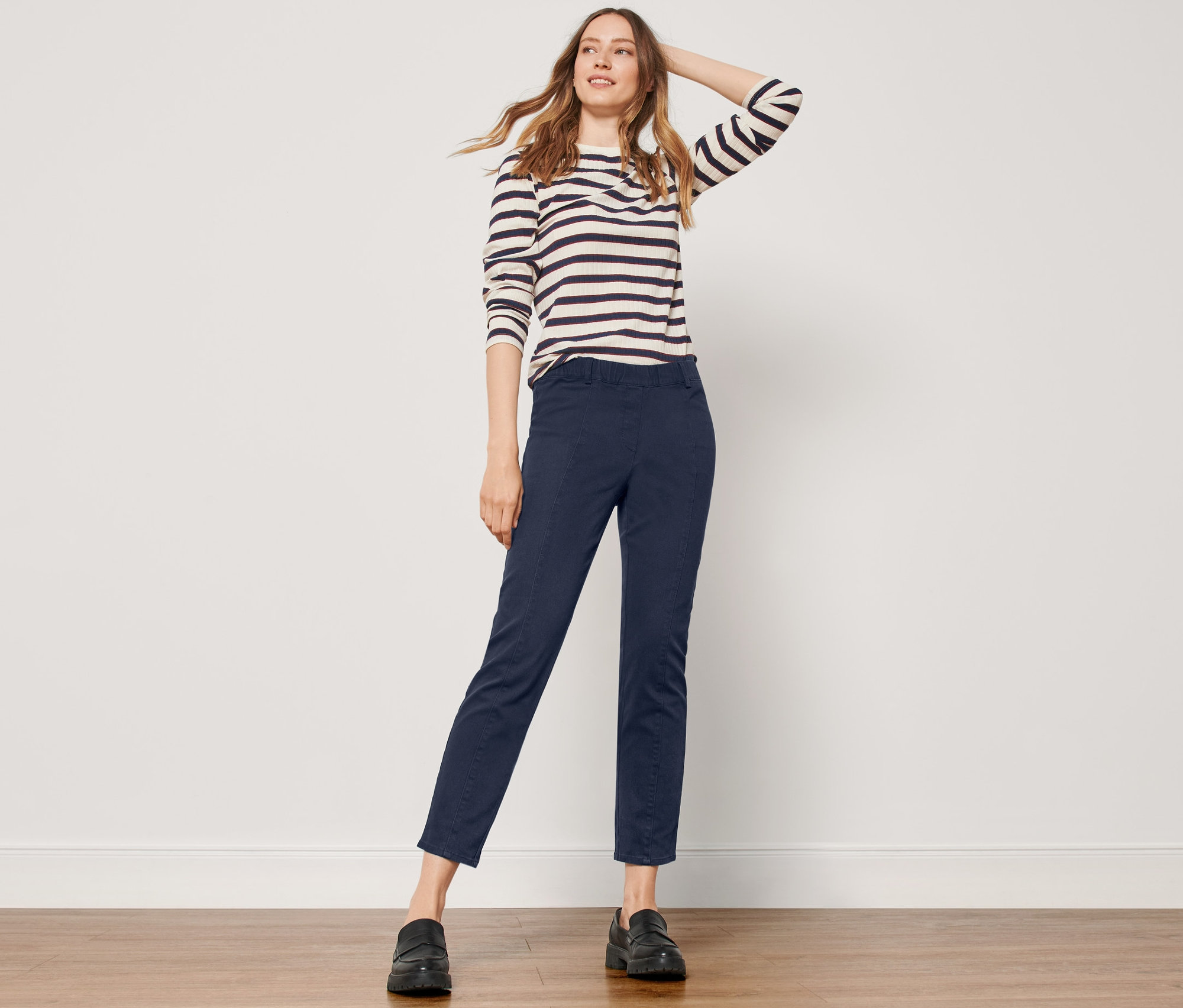 Femme posant en pantalon twill avec ceinture confort, bleu foncé et un haut rayé à manches longues.