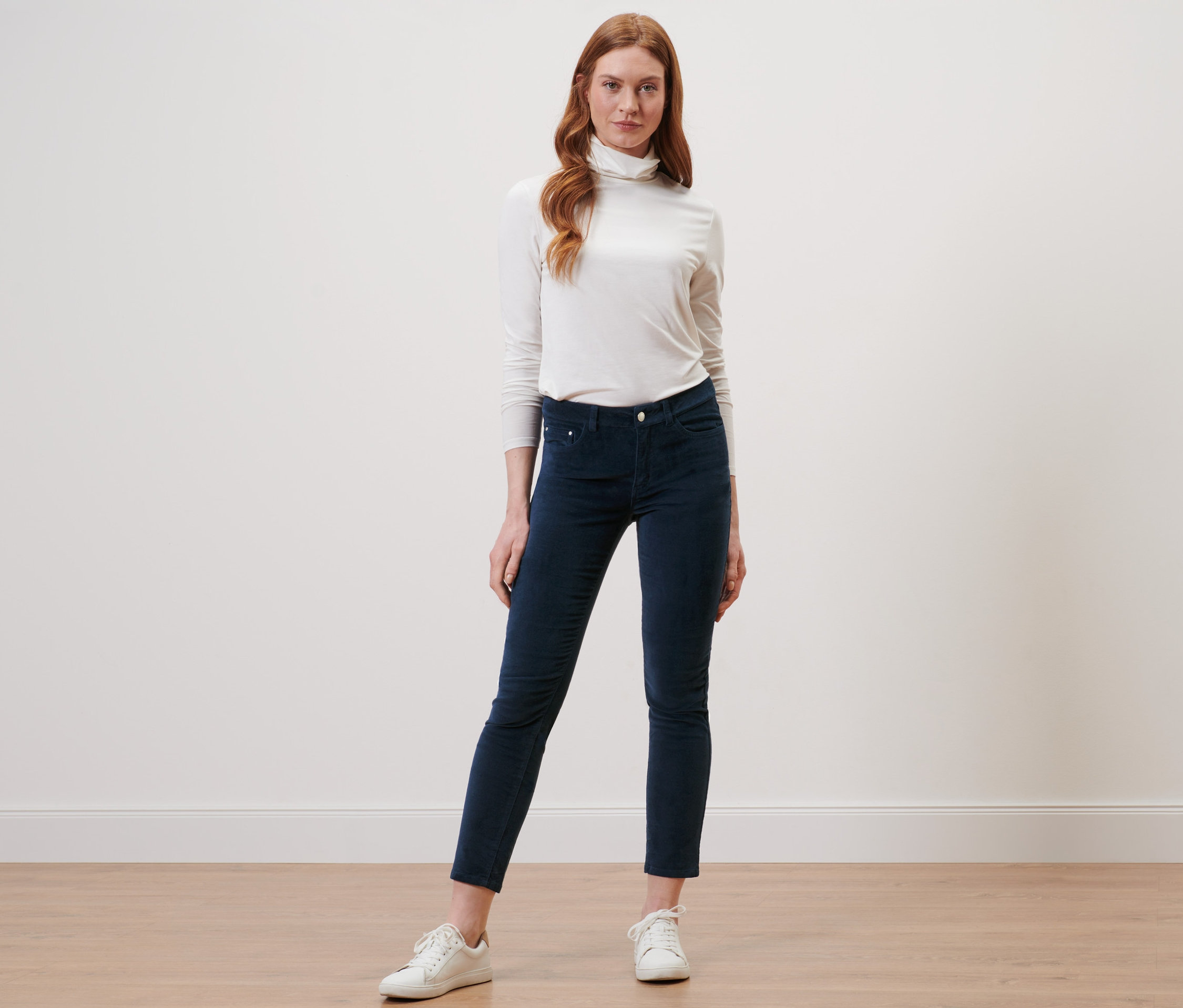 Rousse posant en pantalon de velours bleu foncé.
