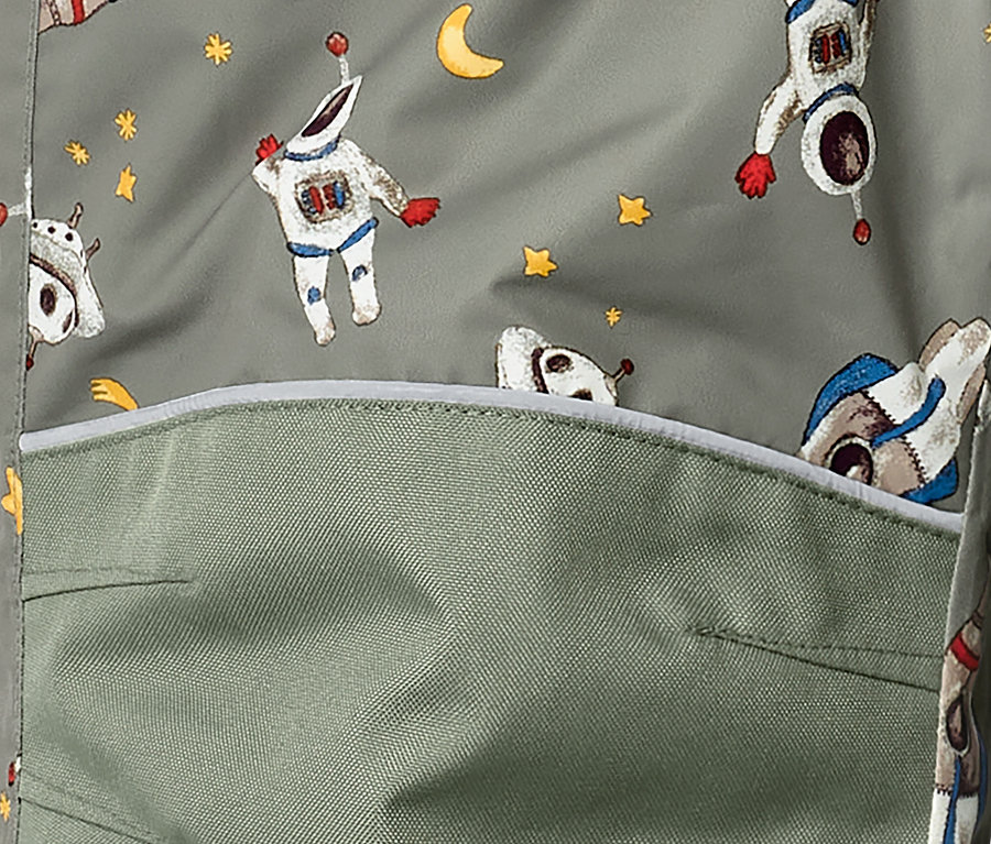 Détail d'une combinaison de ski pour enfant avec un motif d'astronaute et une poche.