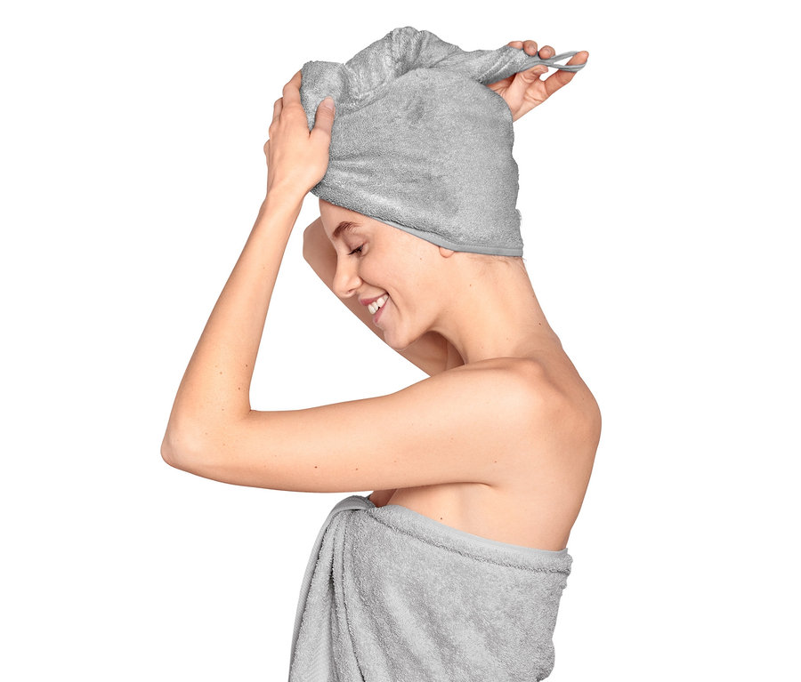 Femme mettant une serviette turban et enveloppée dans une serviette.