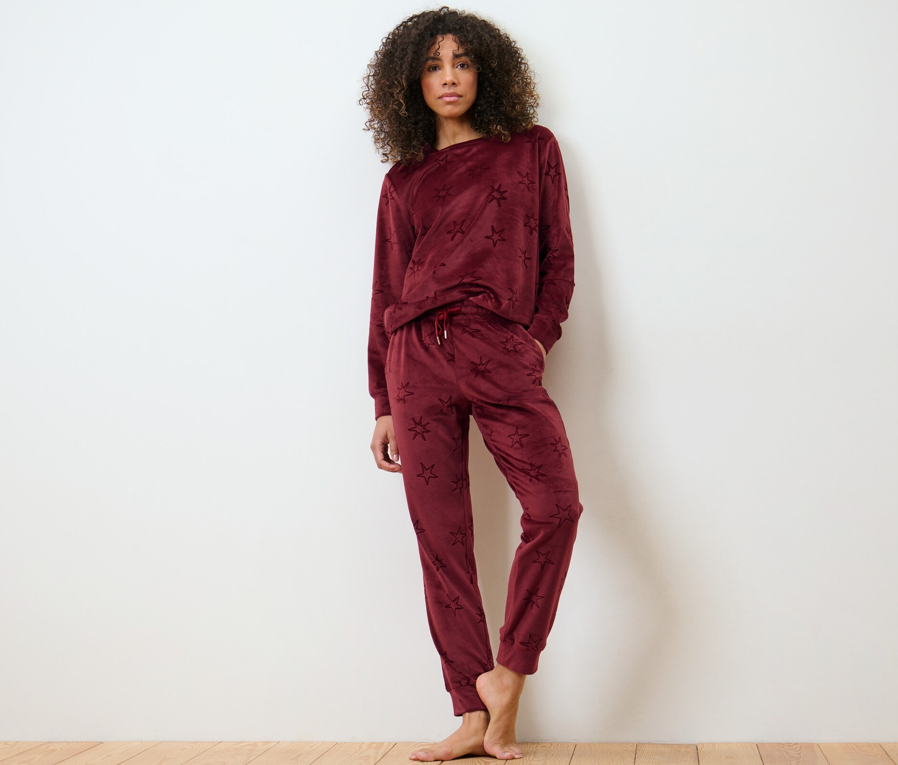 Femme posant sur un plancher en bois en survêtement d’intérieur en velours ras.