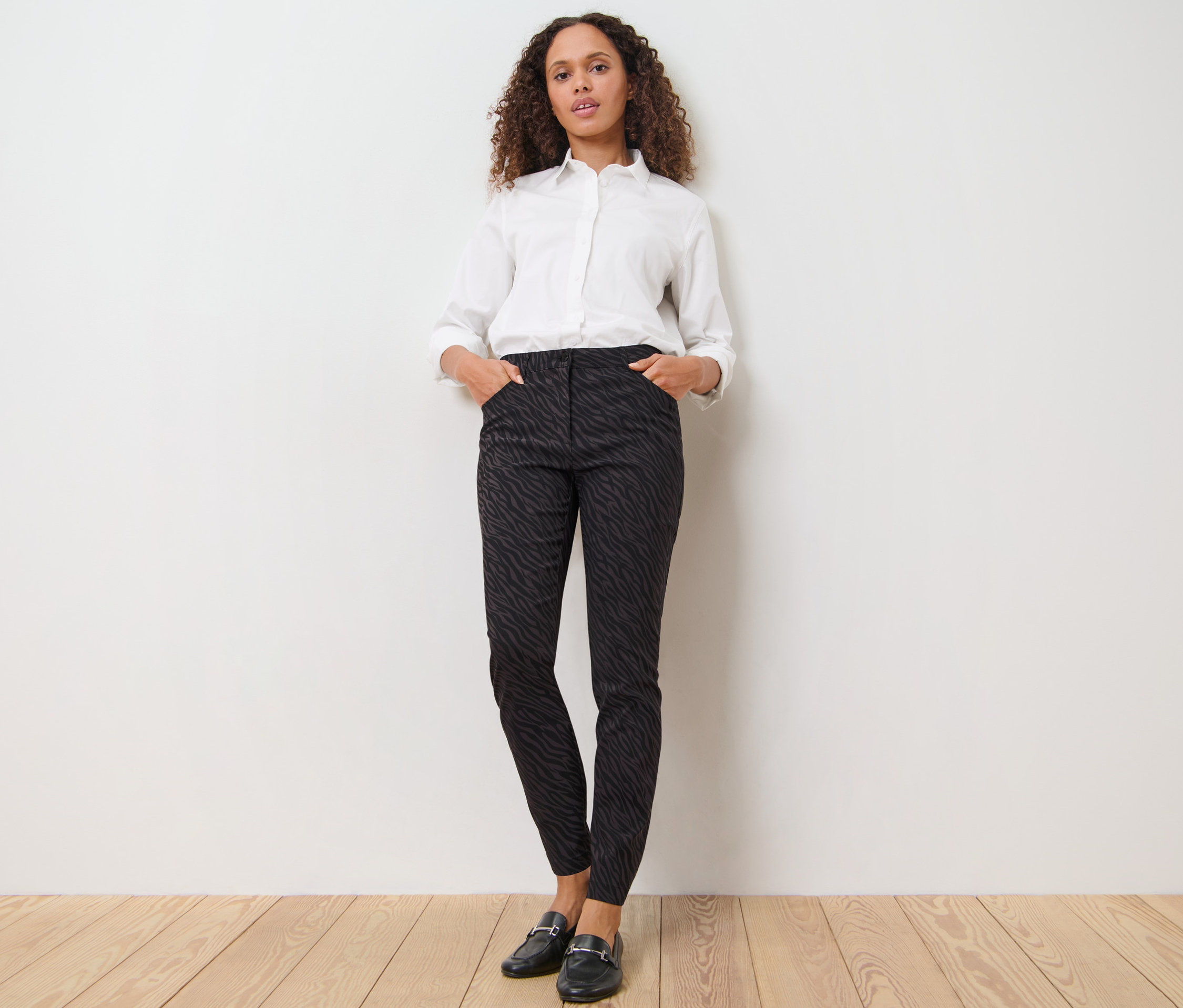 Femme posant en pantalon imprimé en bengaline et chemise blanche.