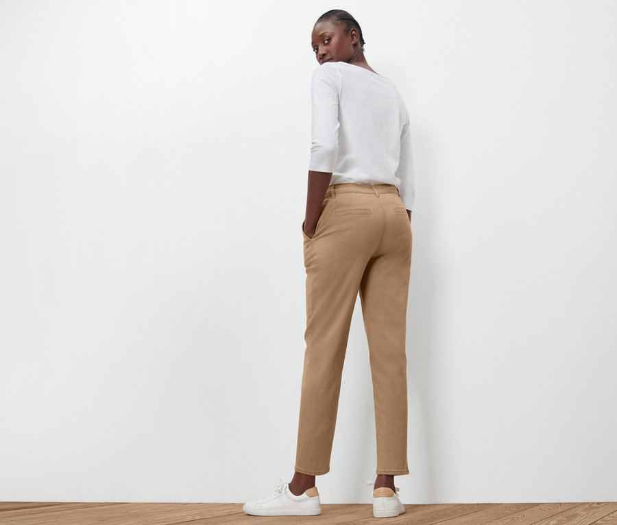 Femme regardant par-dessus son épaule, posant en pantalon chino beige.