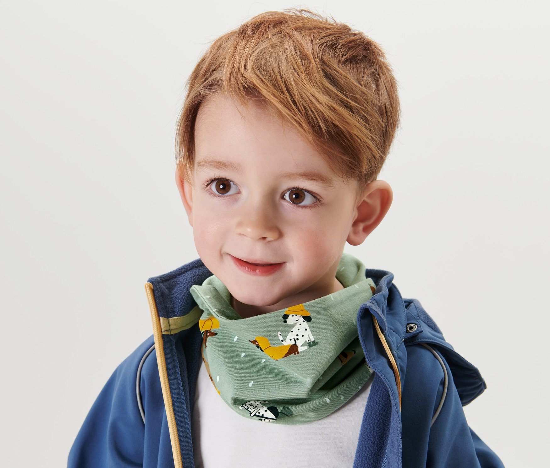 Jeune garçon aux cheveux bruns portant un foulard pour enfant avec bande auto-agrippante.