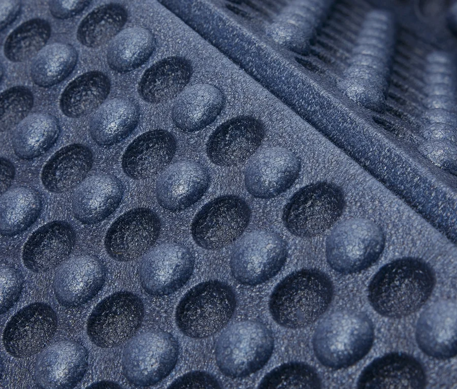 Gros plan sur un tapis isolant pliable bleu avec des cavités circulaires et des rainures.