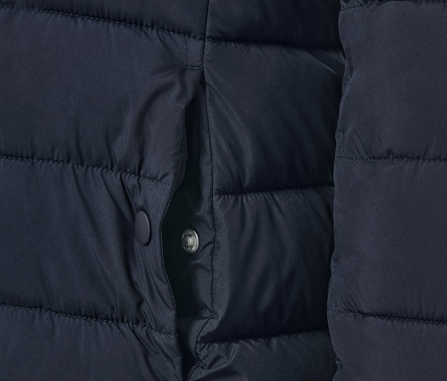 Détail d'une veste matelassée bleu foncé avec une poche.