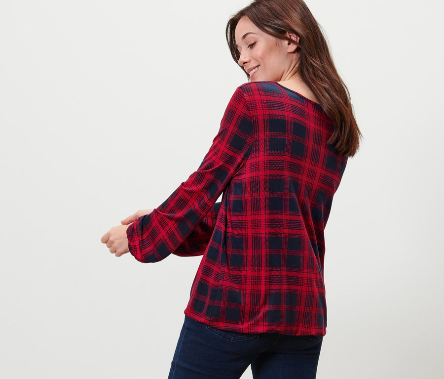 Femme regardant par-dessus son épaule portant une blouse à carreaux et un jean.