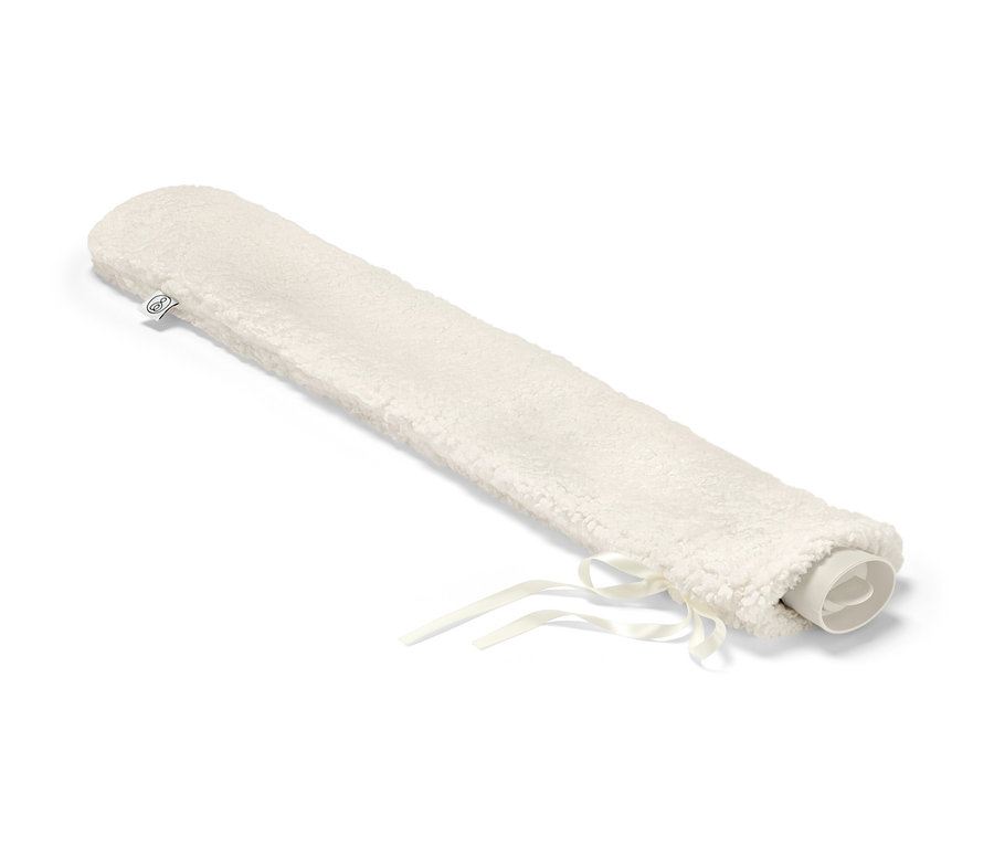 Une bouillotte tube dans une housse en peluche crème avec des rubans.