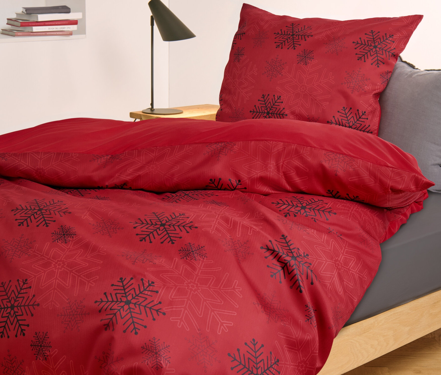 Une parure de lit rouge en microfibre et flanelle avec motif de flocons de neige est sur un lit.