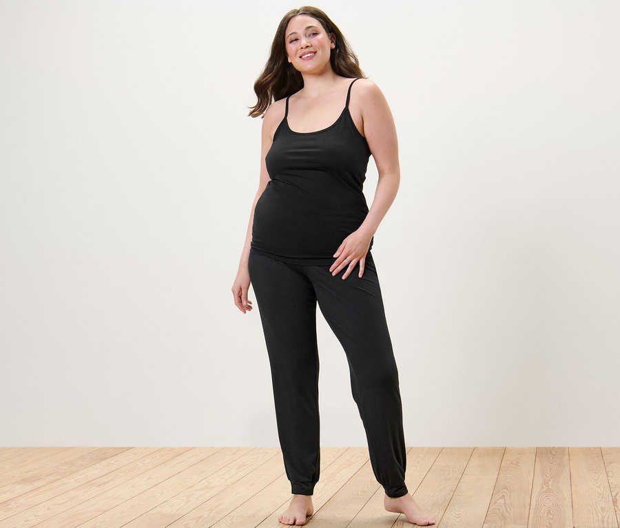 Femme portant un pantalon de pyjama et 2 débardeurs à bretelles fines.