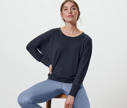 Femme assise sur un tabouret portant un t-shirt de sport et de yoga bleu marine.