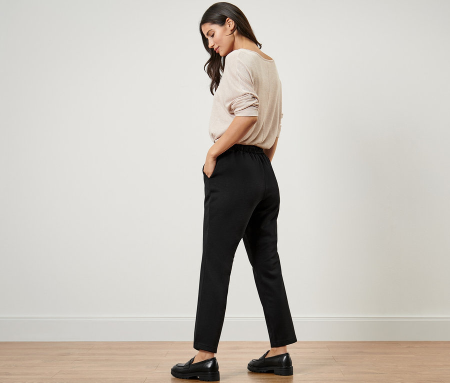 Femme avec les mains dans les poches d'un pantalon de jogging noir.