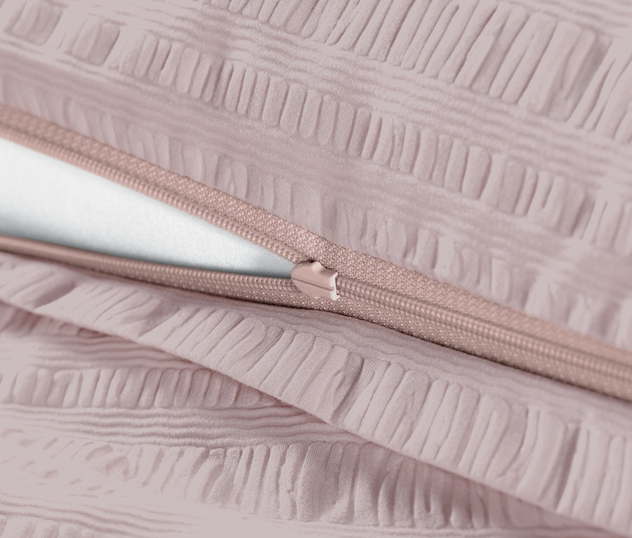 Gros plan d'une parure de lit en seersucker rose avec fermeture éclair.