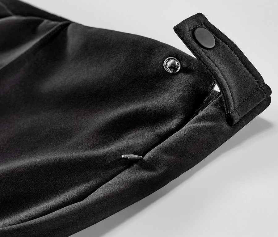 Détail d'un legging de ski en softshell avec poche zippée et fermeture à bouton-pression.