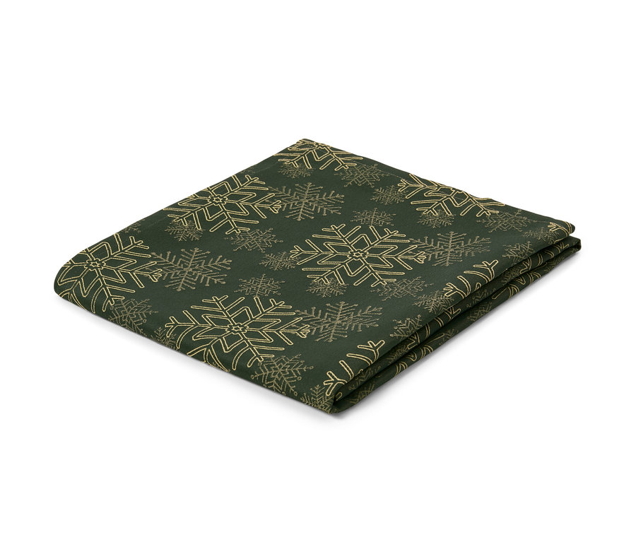 Une nappe en jacquard verte avec un motif de flocons de neige, pliée sur un fond blanc.