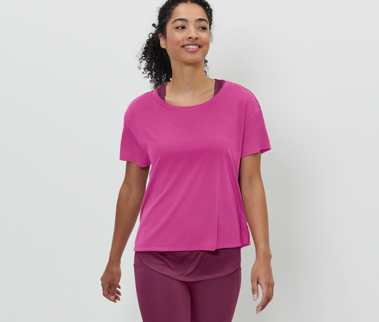 Femme marchant et portant un t-shirt de sport à manches courtes 2 en 1 rose vif.