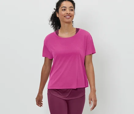 Femme marchant et portant un t-shirt de sport à manches courtes 2 en 1 rose vif.