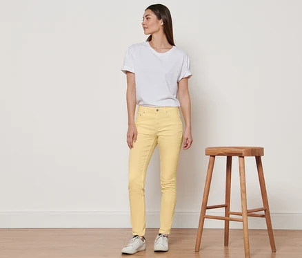 Une femme debout portant un jean Colored Denim « Fit Emma » jaune et un t-shirt blanc.